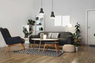 Gri kanepesi, koltuğu ve parlak lambaları olan şık bir oturma odası.