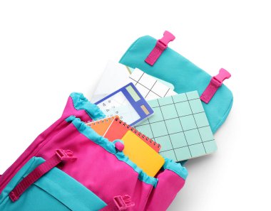 Beyaz arkaplanda kırtasiye malzemesi olan renkli okul çantası, yakın plan