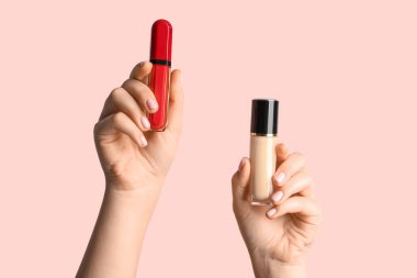 Sıvı makyaj fondöten şişesi ve arka planda ruj izi olan kadın elleri, yakın plan.