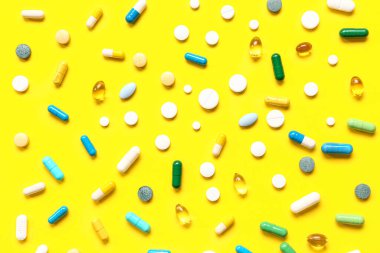 Balık yağı kapsülleri ve sarı arka planda farklı haplar.