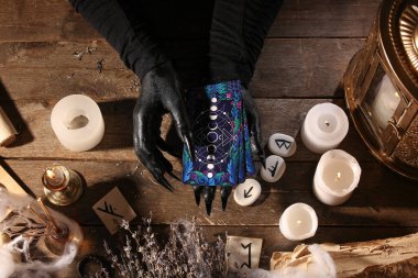 Koyu ahşap masa üzerinde tarot kartları olan bir cadı.