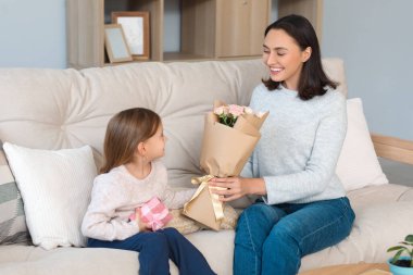 Şirin küçük kızı, güzel annesini hediye kutusu ve gül buketiyle karşılıyor. Anneler Günün kutlu olsun.