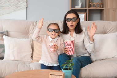 Güzel anne ve üç boyutlu sinema gözlüklü tatlı kızı evde patlamış mısır izleyip film izliyorlar.