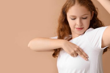 Bej arka planda göğüslerini kontrol eden genç bir kadın. Kanser farkındalığı kavramı