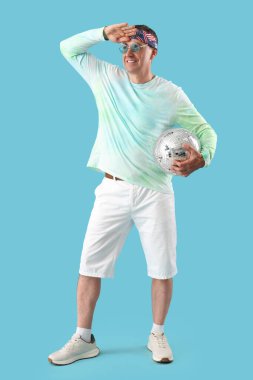 Havalı olgun adam disko topuyla mavi arka planda selam veriyor.