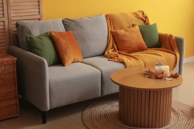 Gri kanepesi ve kahve masasında sonbahar yaprakları olan şık bir oturma odası.