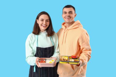 Mavi arka planda beslenme çantası olan genç bir çift.