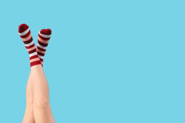 Mavi arka planda çizgili çoraplı genç kadın bacakları