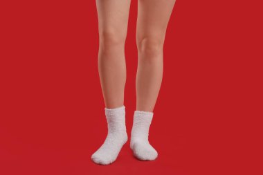 Kırmızı arka planda beyaz, sıcak çoraplı genç kadın bacakları.