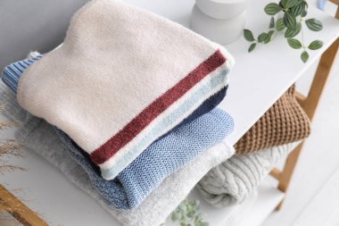 Raflarda farklı stil süveterler var, oda içinde, yakın plan.