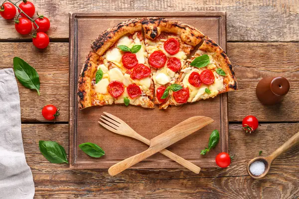 Board with slices of tasty pizza Margarita and fresh tomatoes on wooden background