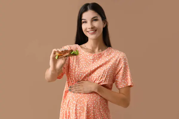 Junge Schwangere Frau Mit Leckerem Sandwich Auf Farbigem Hintergrund — Stockfoto