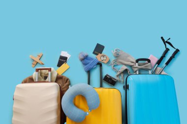 Mavi arka planda seyahat aksesuarları olan bavullar, üst görünüm