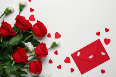 Karanfilli kırmızı güller, beyaz arka planda zarf ve kalpler. Sevgililer Günü konsepti