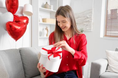 Güzel bir kadın sevgililer gününde evde hediye kutusunu açıyor.