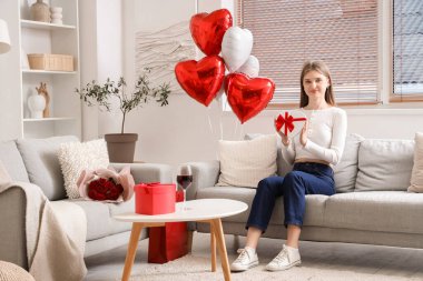 Sevgililer Günü 'nde evde oturan hediye kutusuyla güzel bir kadın.