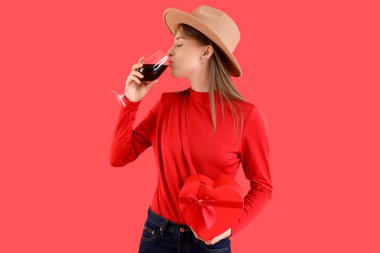 Kırmızı arka planda şarap içen güzel bir kadın. Sevgililer Günü kutlaması