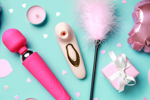 Разные секс-игрушки и свечи на синем фоне. Празднование Дня Святого Валентина