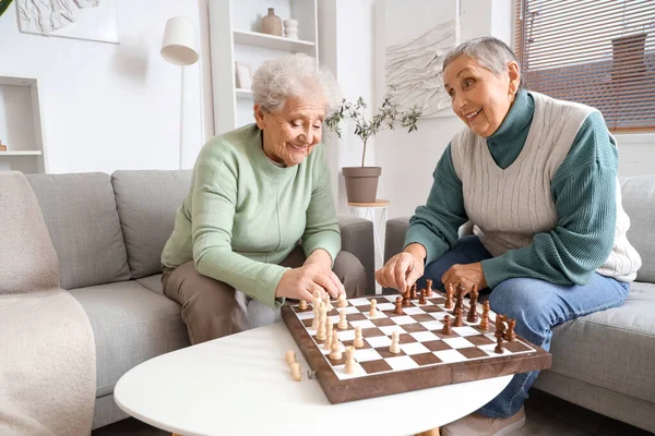 Senior female friends playing chess at home