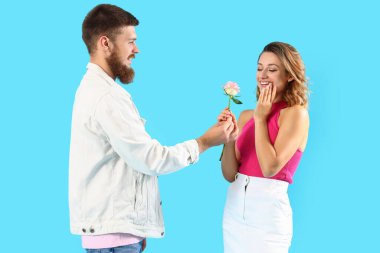 Genç adam Rose 'u mavi arka planda kız arkadaşına veriyor.