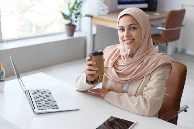 Ofiste çalışan bir fincan kahveli güzel Müslüman kadın programcı.