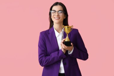 Pembe arka planda altın kupalı genç bir iş kadını.