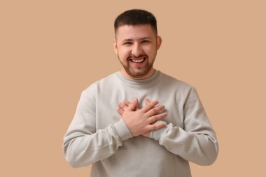 Yakışıklı genç adam bej arka planda gülüyor.