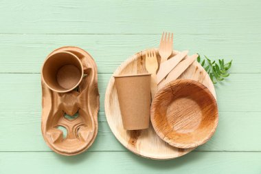 Yeşil ahşap arka planda bitki dalları olan eko sofra takımı