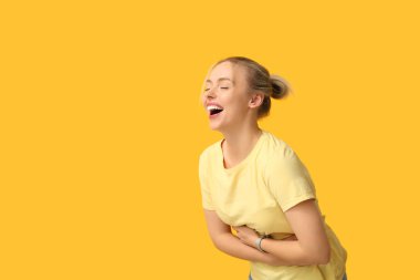 Güzel, mutlu, genç bir kadın sarı arka planda gülüyor.