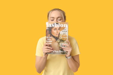 Güzel, mutlu, genç bir kadın ve dergi sarı arka planda gülüyor.