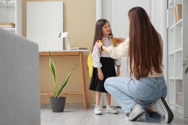 Anne küçük kızını evde okula hazırlıyor.