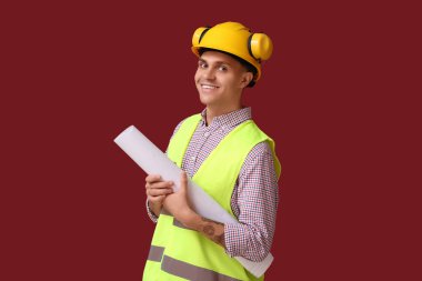 Kırmızı arka planı olan genç bir erkek mühendis.