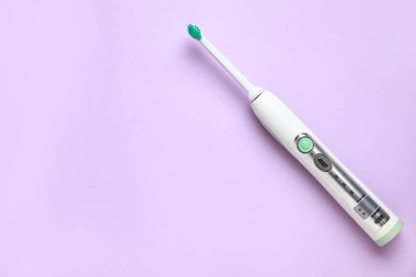 Leylak arkaplanda modern elektrikli diş fırçası. Dünya Diş Hekimi Günü