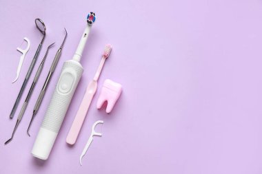 Diş fırçaları, diş aletleri, diş modelleri ve leylak arka planda diş ipi kürdanları. Dünya Diş Hekimi Günü