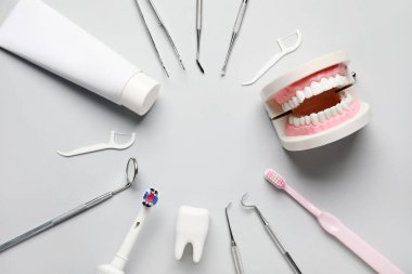 Diş aletlerinden yapılmış çerçeve, ağız temizliği malzemeleri ve beyaz arka planda plastik modeller. Dünya Diş Hekimi Günü