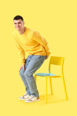 Hemoroidli genç bir adam ve sarı arka planda sandalyede raptiye.