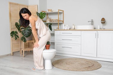 Tuvalette hemoroit ve kaktüslü genç bir Asyalı kadın.