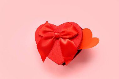 Pembe arka planda kağıt kalpli bir hediye kutusu. Sevgililer Günü kutlaması