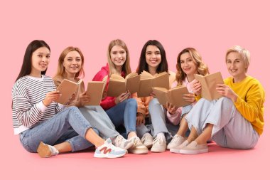 Pembe arka planda kitapları olan güzel kadınların portresi