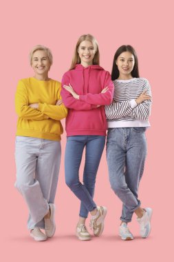 Pembe arka planda çapraz kollu güzel kadınların portresi.