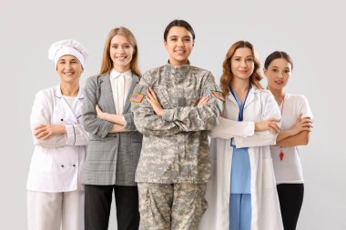 Gri arka planda çapraz kollu farklı meslekten kadınlar.