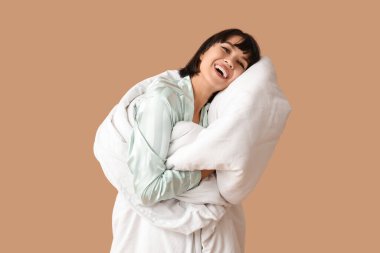 Kahverengi arka planda battaniyeli pijamalı güzel bir kadın.