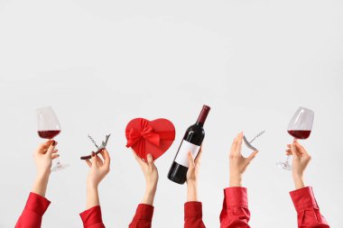 Kırmızı şarap, hediye ve arka planda tirbuşonu olan kadınlar. Sevgililer Günü kutlaması