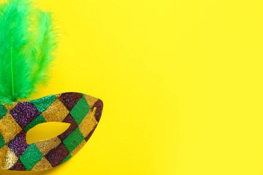 Sarı arka planda Mardi Gras kutlaması için tüylü parlak karnaval maskesi.