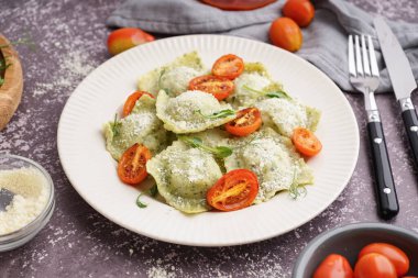 Gri arkaplanda domatesli ve peynirli lezzetli ravioli tabağı