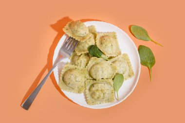 Turuncu arka planda sebzeli lezzetli ravioli tabağı.