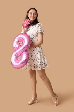 Kahverengi arka planda 8 şeklinde pembe hava balonu olan güzel genç bir kadın. Uluslararası Kadınlar Günü