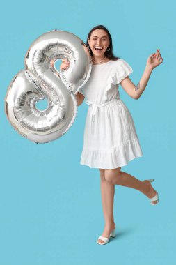 Mavi arka planda gümüş renkli hava balonu olan mutlu genç bir kadın. Uluslararası Kadınlar Günü