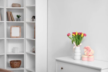 İçinde laleler ve hediye kutuları olan vazolar oturma odasında klozette. Uluslararası Kadınlar Günü kutlamaları