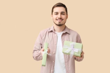 Bej arka planda hediye kutuları olan genç bir adam. Uluslararası Kadınlar Günü